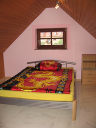 Ausschnitt des Zimmers 'Perls' mit Bett, Schrank und Fenster