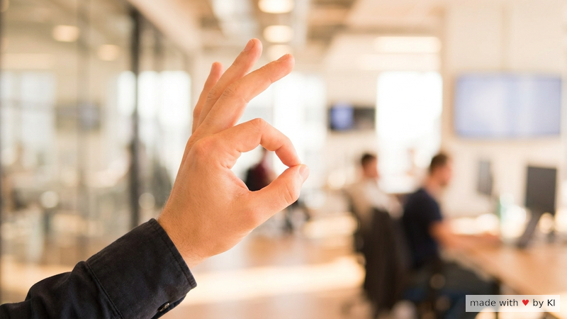 Eine Hand drückt einen Daumen an den Zeigefinger als Anker-Geste vor einem Bürofenster im Sonnenlicht - Selbsthypnose-Reset zwischen Terminen